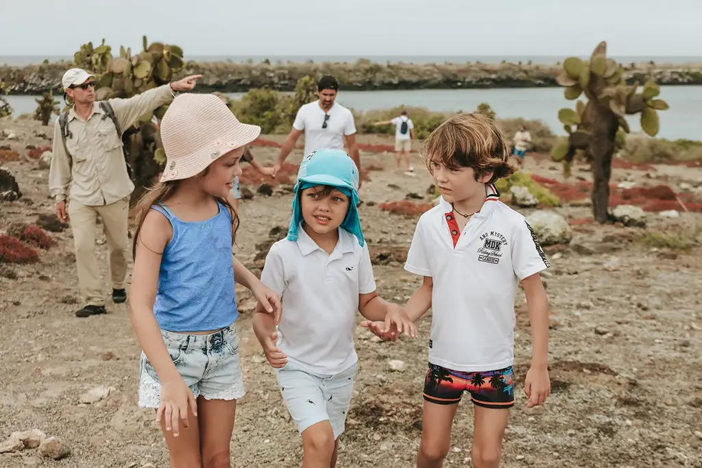 Children and a guide walking among giant cacti