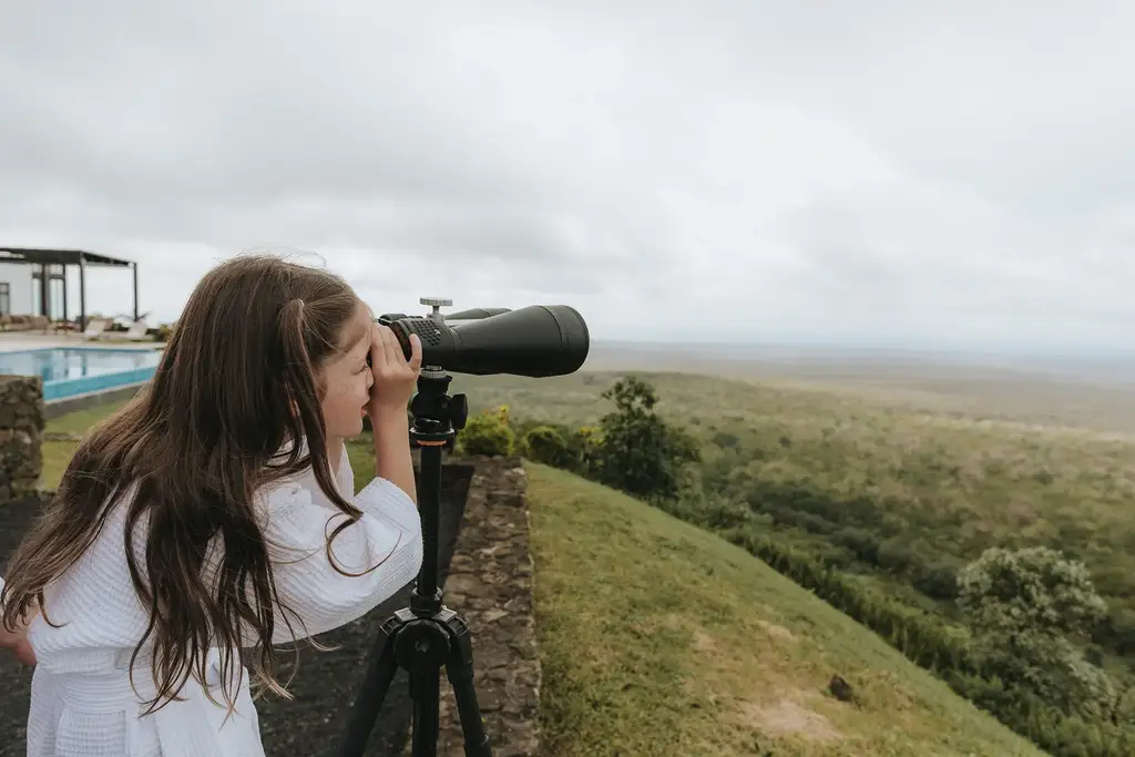 A young explorer looking through a telescope over the Galápagos highlands