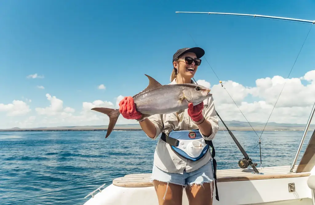 Guest holding a catch aboard a Galápagos fishing excursion
