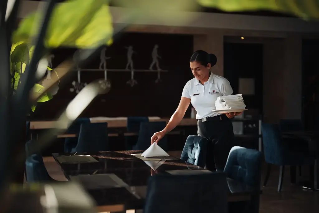 Server setting a table at Evolution by Pikaia restaurant